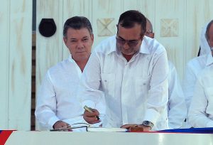 BOG126. CARTAGENA (COLOMBIA), 26/09/2016.- El máximo líder de las Fuerzas Armadas Revolucionarias de Colombia (FARC), Rodrigo Londoño Echeverri (frente), alias alias "Timochenko", firma el acuerdo de paz frente al presidente de Colombia, Juan Manuel Santos (i), hoy, lunes 26 de septiembre de 2016, en la ceremonia de la firma del acuerdo de paz en la ciudad de Cartagena (Colombia). Santos y Londoño Echeverri firmaron hoy el acuerdo de paz que pone fin a más de medio siglo de conflicto armado. El acuerdo es fruto de casi cuatro años de diálogos entre el Gobierno y las FARC en La Habana y fue sellado en Cartagena de Indias ante más de 2.500 invitados, entre ellos unos 15 presidentes y el rey Juan Carlos. EFE/Mauricio Dueñas Castañeda