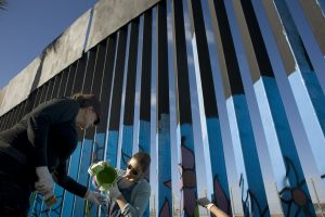 Victoria Dowding (i) and Getsemani Bustillos ayudan en la elaboración de murales en la cerca que marca el límite en la frontera entre EE.UU. y México hoy, jueves 1 de diciembre de 2016, durante el primer día de la realización de este proyecto en Tijuana (México). Un grupo de artistas inició hoy un proyecto sin precedentes bajo el cual cientos de voluntarios de distintas partes del mundo se unirán para ponerle color a más de dos mil metros lineales del muro fronterizo entre México y Estados Unidos. EFE