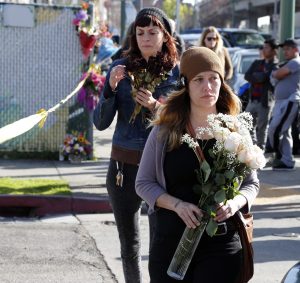Two woman arrive to leave flowers at the scene of a warehouse fire in the Fruitvale district of Oakland, California, USA, 04 December 2016. At least 30 people are confirmed dead, according to officials. The fire broke out during a musical performance late on 02 December. EFE