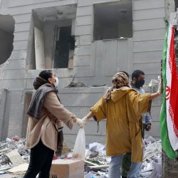 Dos hermanas iraníes se dan la mano frente a un edificio dañado en el sur de Teherán, Irán, el 15 de marzo de 2026. EFE/EPA/ABEDIN TAHERKENAREH
